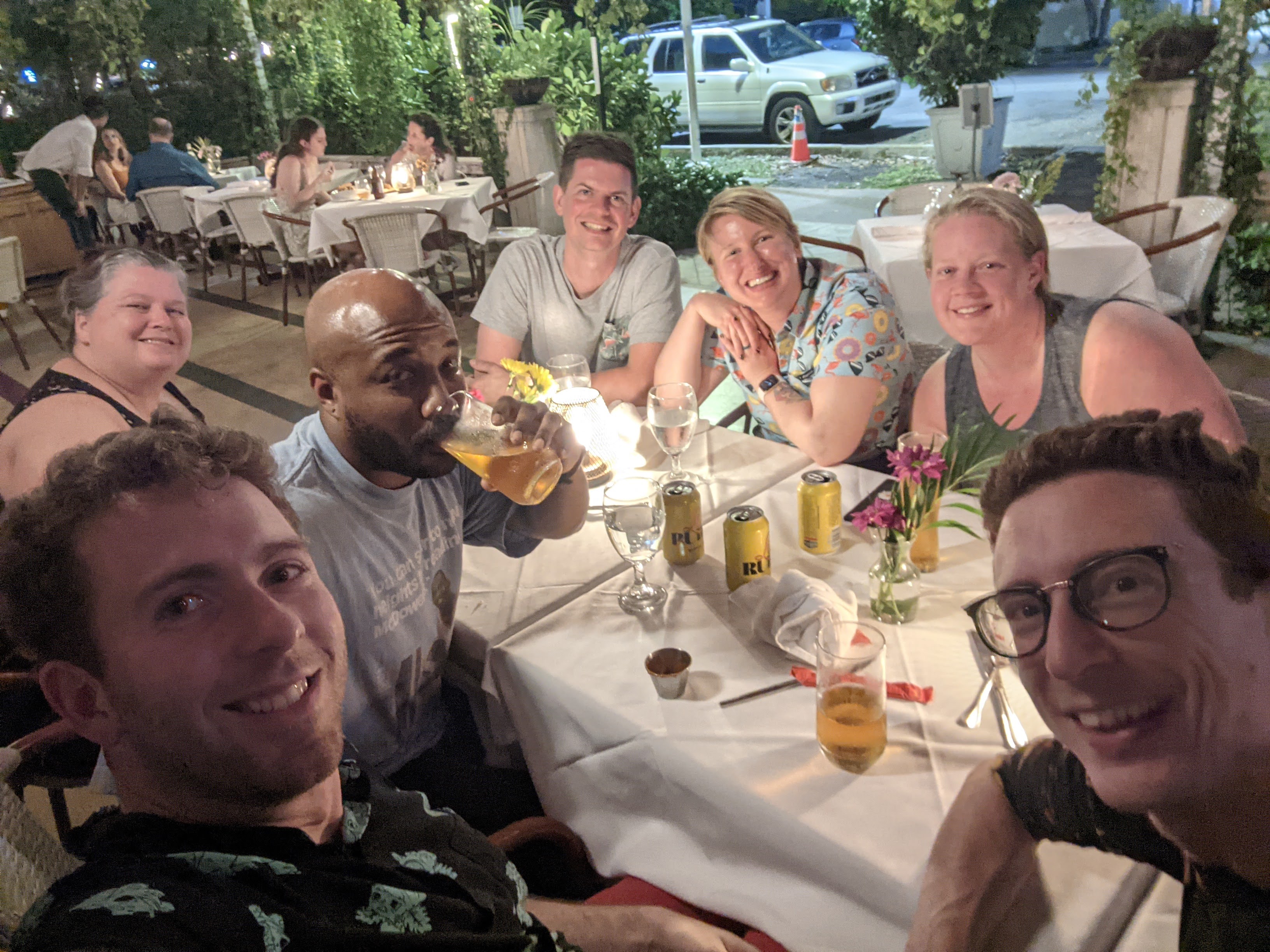 Smiling selfie of a group of people at an outdoor dinner table.